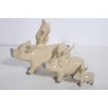 A SET OF THREE GRADUATED GLAZED PORCELAIN FIGURES modelled as flying pigs the larger 26cm (h)