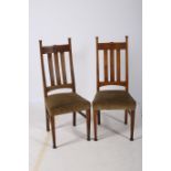 A PAIR OF ARTS AND CRAFTS OAK SIDE CHAIRS each with a shaped top rail and carved panel with