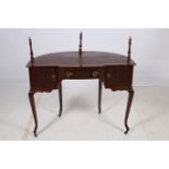 A MAHOGANY DESK of demilune outline the shaped top with tooled leather inset and frieze drawer with