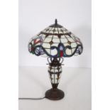 A TIFFANY DESIGN BRONZED TABLE LAMP the multicoloured shade above a baluster column on a circular