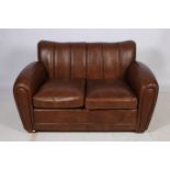 A RETRO HIDE UPHOLSTERED TWO SEATER SETTEE the rectangular panelled back with loose cushions and