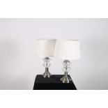 A PAIR OF WHITE METAL AND CUT GLASS TABLE LAMPS each with a faceted urn column above a circular