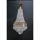 A CONTINENTAL GILT BRASS AND CUT GLASS CHANDELIER with cascading pendent drops above three