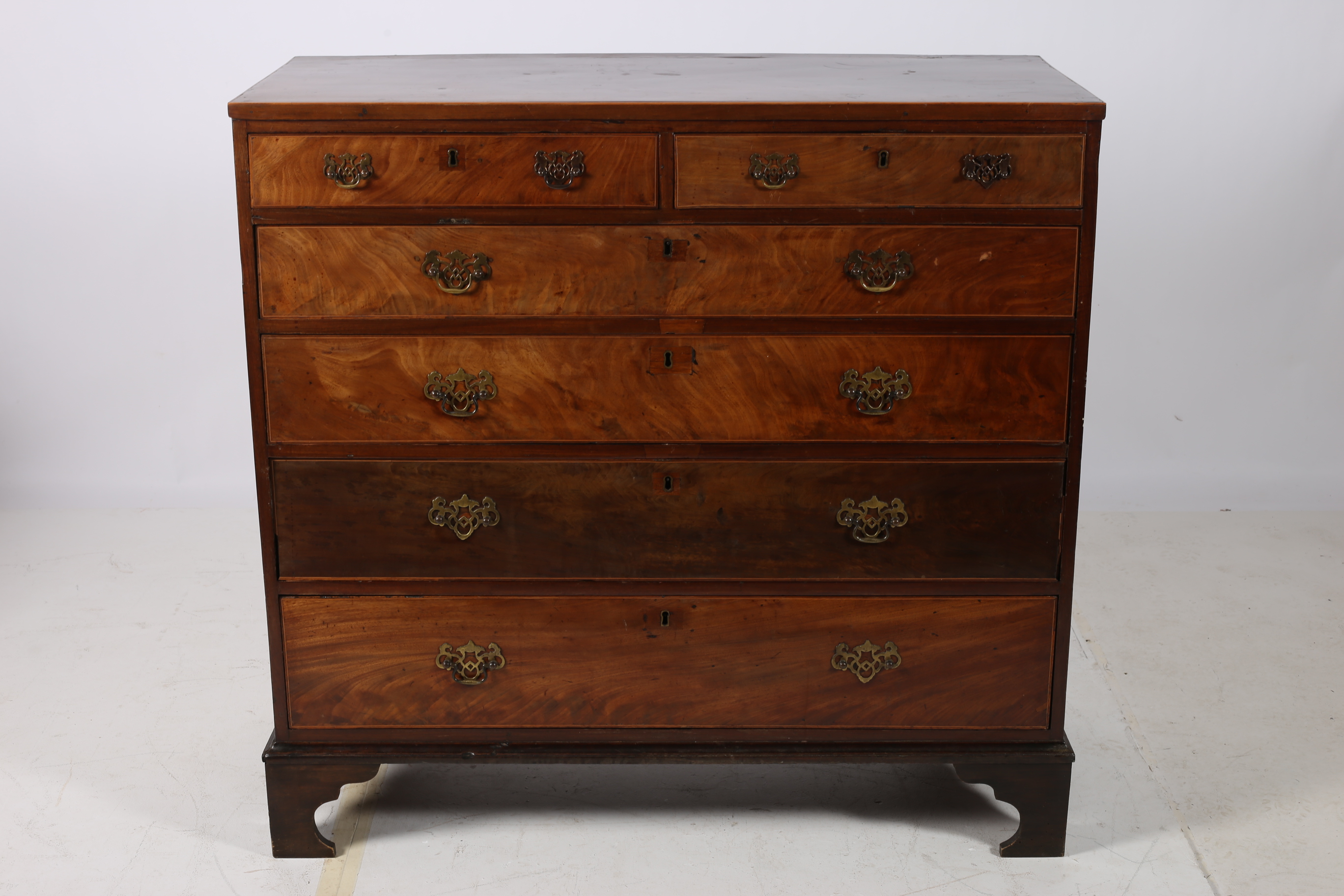 A GEORGIAN MAHOGANY AND SATINWOOD INLAID CHEST of rectangular outline the shaped top with two short