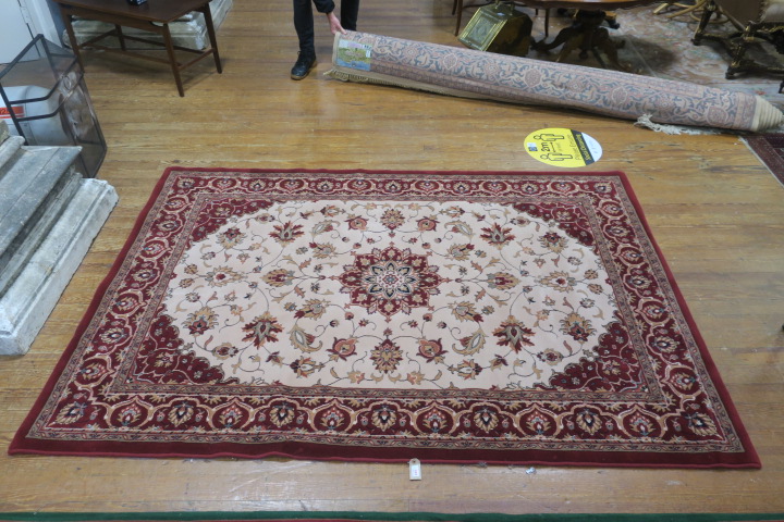 A WOOL RUG the light pink and wine ground with central floral panel within a conforming border