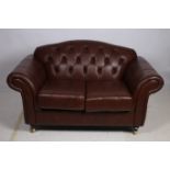 A VICTORIAN DESIGN HIDE UPHOLSTERED TWO SEATER SETTEE with deep button upholstered back and loose