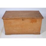 A PINE TRUNK of rectangular outline the hinged lid containing lidded compartment with drawers on