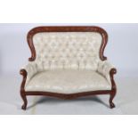 A MAHOGANY AND UPHOLSTERED SETTEE the shaped top rail with foliate carved decoration above a button