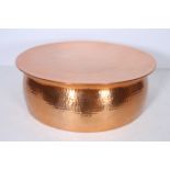 A HAMMERED COPPER COFFEE TABLE of circular outline with waisted frieze 29cm (h) x 81cm (d)