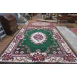 AN EMERALD GREEN AND BEIGE GROUND PATTERNED RUG the central panel filled with flowerheads and