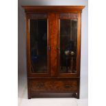 AN ARTS AND CRAFTS MAHOGANY AND WALNUT TWO DOOR WARDROBE the outswept moulded cornice above a pair
