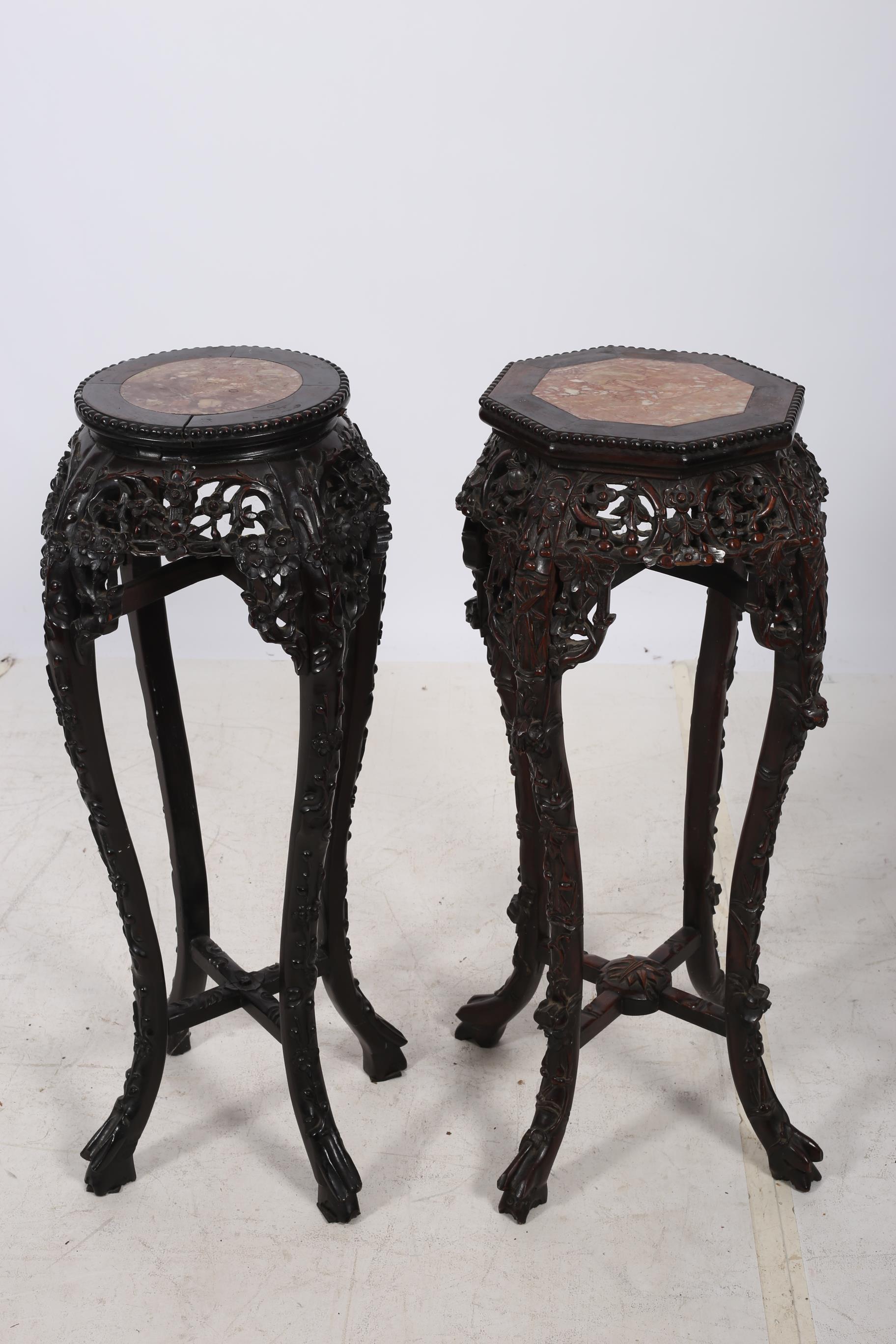 TWO ORIENTAL CARVED JARDINIERE STANDS each with a rouge veined marble inset above a pierced frieze