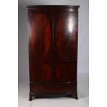 A 19TH CENTURY MAHOGANY CROSS BANDED WARDROBE of demilune outline the dentil moulded cornice above