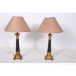 A PAIR OF CONTINENTAL GILT AND BLACK TABLE LAMPS each with a cylindrical spreading column on scroll
