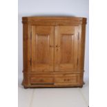 A 19TH CENTURY PINE ARMOIRE the moulded cornice above a pair of panelled doors between canted