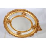 A CONTINENTAL GILTWOOD COMPARTMENTED MIRROR of oval outline with flowerhead foliate and shell