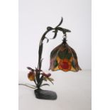 A TIFFANY DESIGN WROUGHT IRON TABLE LAMP with multicoloured glass shade and scroll arm with foliate