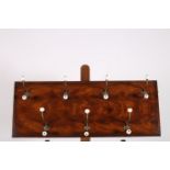 A MAHOGANY WALL MOUNTED HAT AND COAT RACK with seven brass roped hooks and porcelain knobs 36cm x