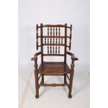 AN OAK SPINDLE BACK ELBOW CHAIR with panelled seat and scroll arms on moulded legs with pad feet