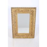 A CONTINENTAL GILT FRAMED MIRROR the rectangular bevelled glass plate within a shell C-scroll and