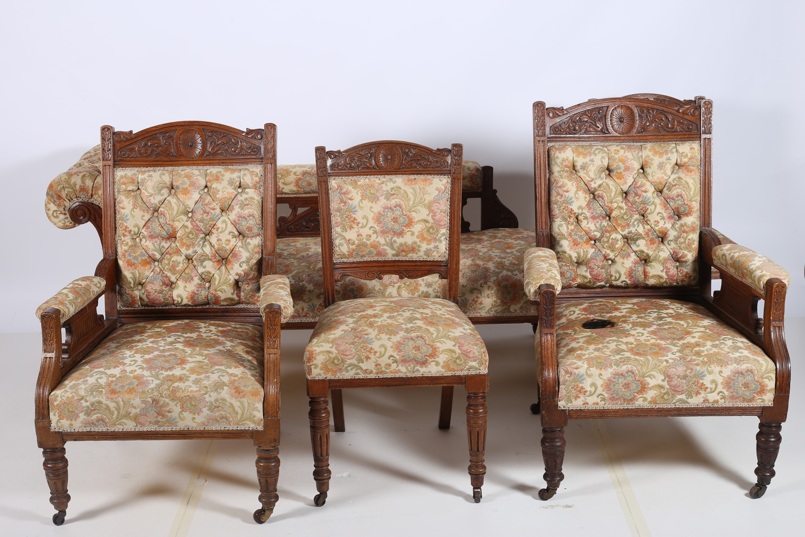 AN EDWARDIAN CARVED OAK AND UPHOLSTERED SEVEN PIECE DRAWING ROOM SUITE comprising set of four