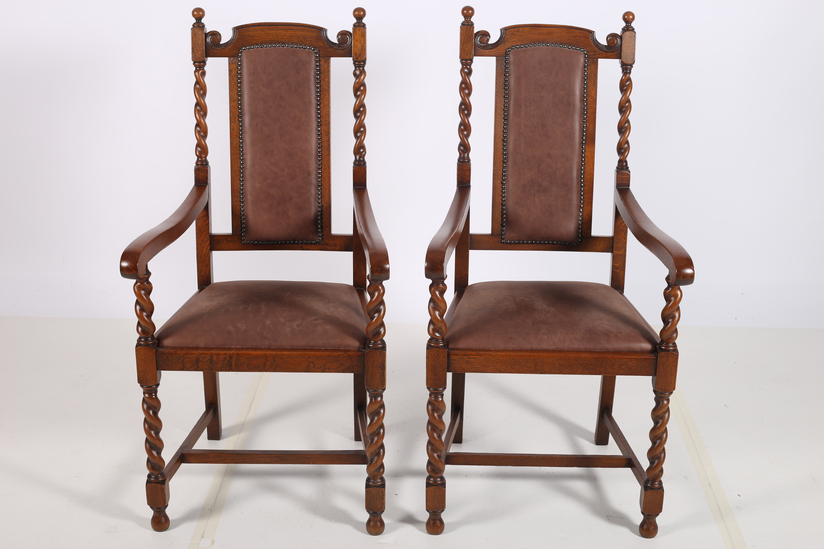 A PAIR OF CIRCA 1950s OAK ELBOW CHAIRS each with upholstered panelled back and seat with spiral