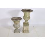 A PAIR OF COMPOSITION STONE GARDEN URNS each of semi lobed Campana form one raised on a pedestal,