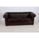 A VICTORIAN DESIGN WINE HIDE UPHOLSTERED THREE SEATER LIBRARY SETTEE with deep button roll over