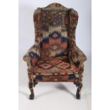 A FINE GEORGIAN IRISH MAHOGANY AND UPHOLSTERED WING CHAIR with loose cushion scroll over arms on