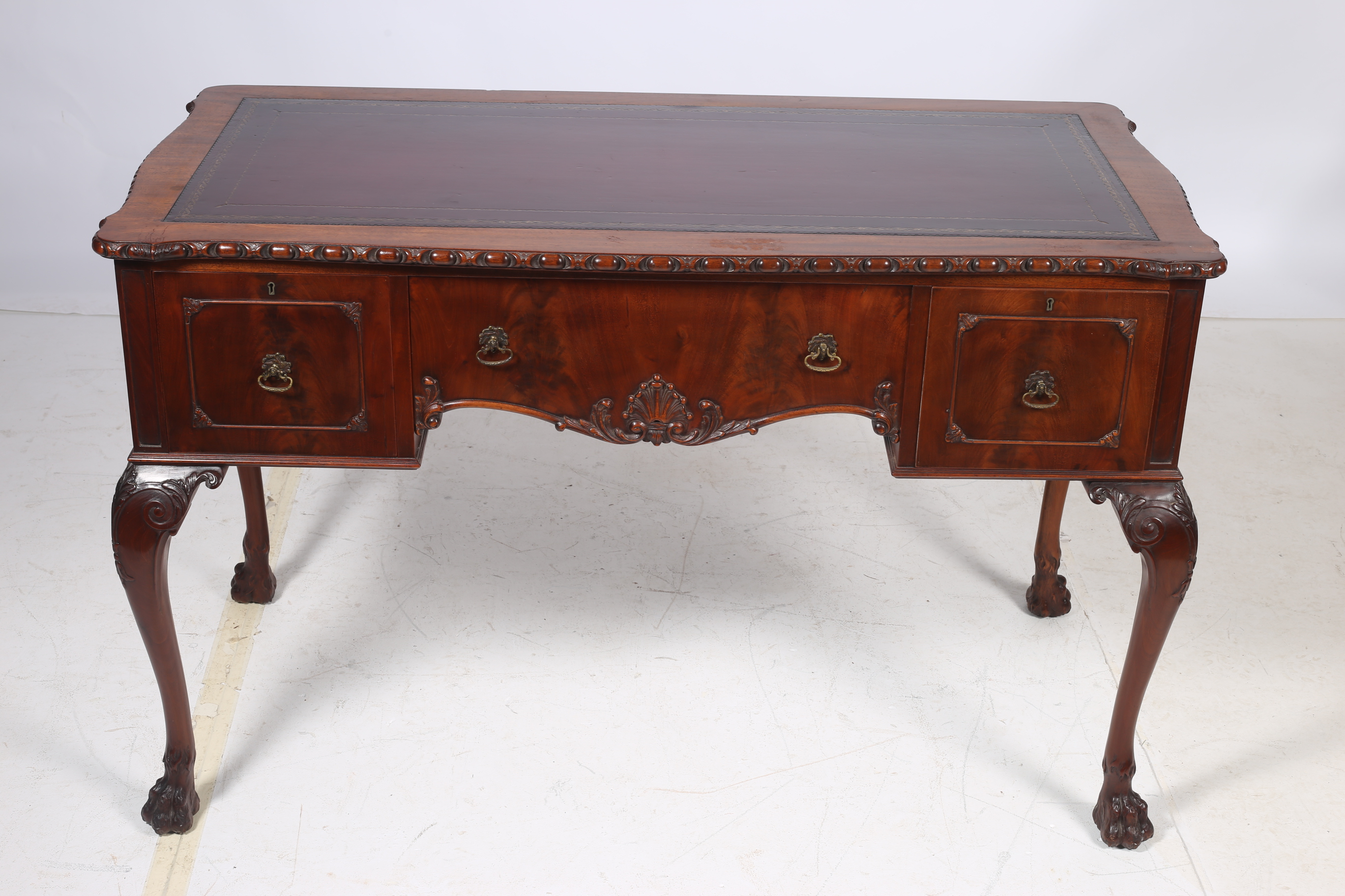 A CHIPPENDALE DESIGN MAHOGANY DESK of serpentine outline the shaped top with gadrooned rim and