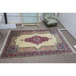 A KIRMAN WOOL RUG the ivory ground with central panel filled with flower heads and foliage within a