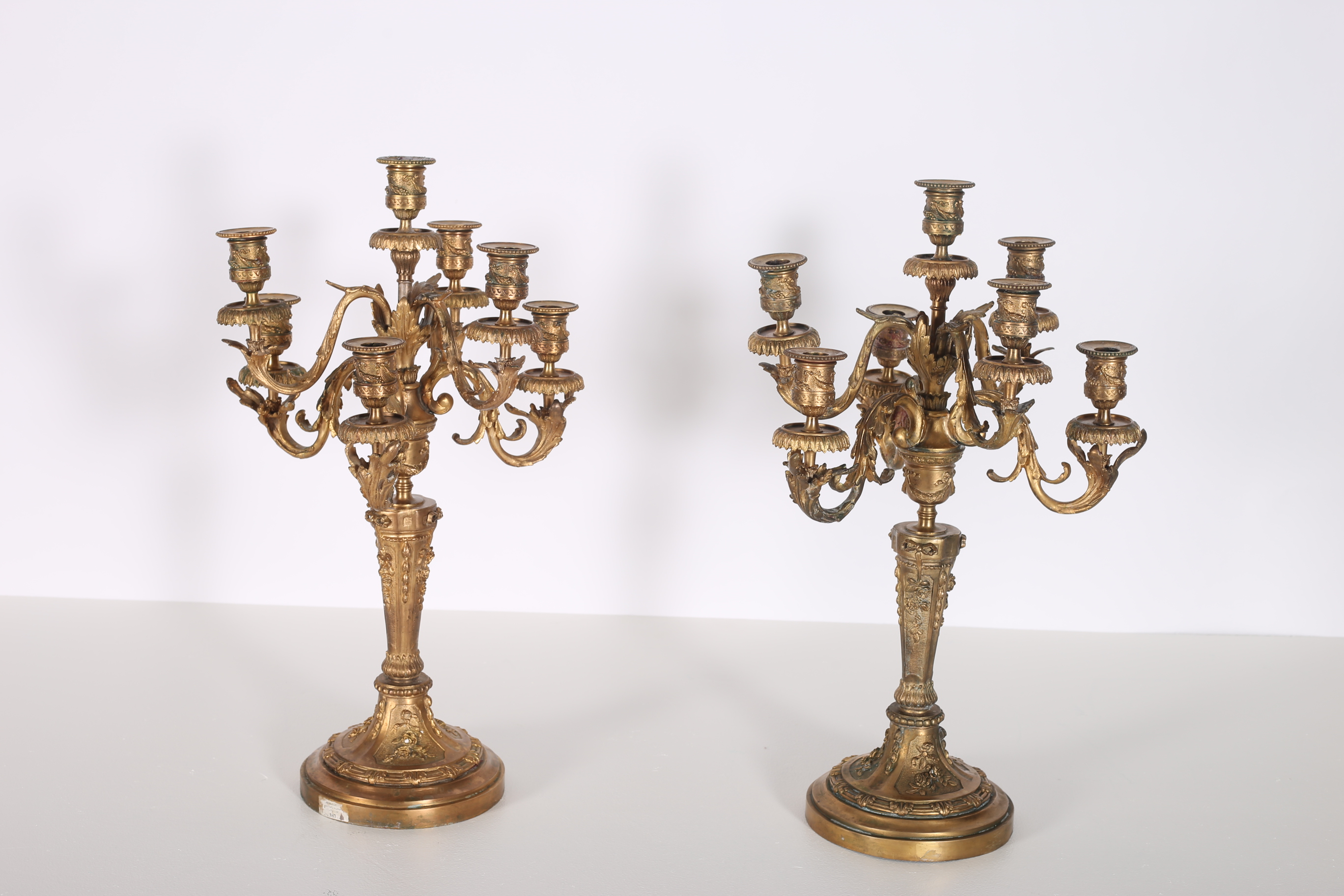 A PAIR OF CONTINENTAL GILT BRASS SEVEN BRANCH CANDELABRAS hung in two registers with foliate cast