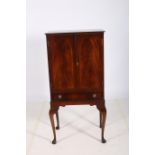 A CIRCA 1950s MAHOGANY COCKTAIL CABINET of rectangular outline the shaped top with blind panelled