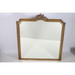 A CONTINENTAL GILTWOOD AND GESSO MIRROR the rectangular arched bevelled glass plate within a bead