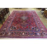 A FINE CAUCASIAN WOOL RUG the wine ground with central panel filled with stylized flowerheads and
