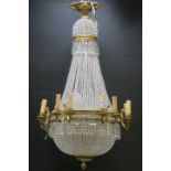 A CONTINENTAL GILT BRASS AND CUT GLASS BASKET CHANDELIER with cascading pendent drops and faceted