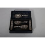 A FIVE PIECE 19TH CENTURY SILVER EMBOSSED DRESSING TABLE SET IN CASE comprising a pair of hair