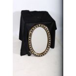 A WATERFORD STYLE EBONISED AND PARCEL GILT MIRROR the oval plate within a moulded frame with