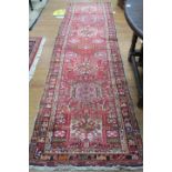 A TURKISH WOOL RUNNER the light red ground with central panel filled with stylized flowerheads