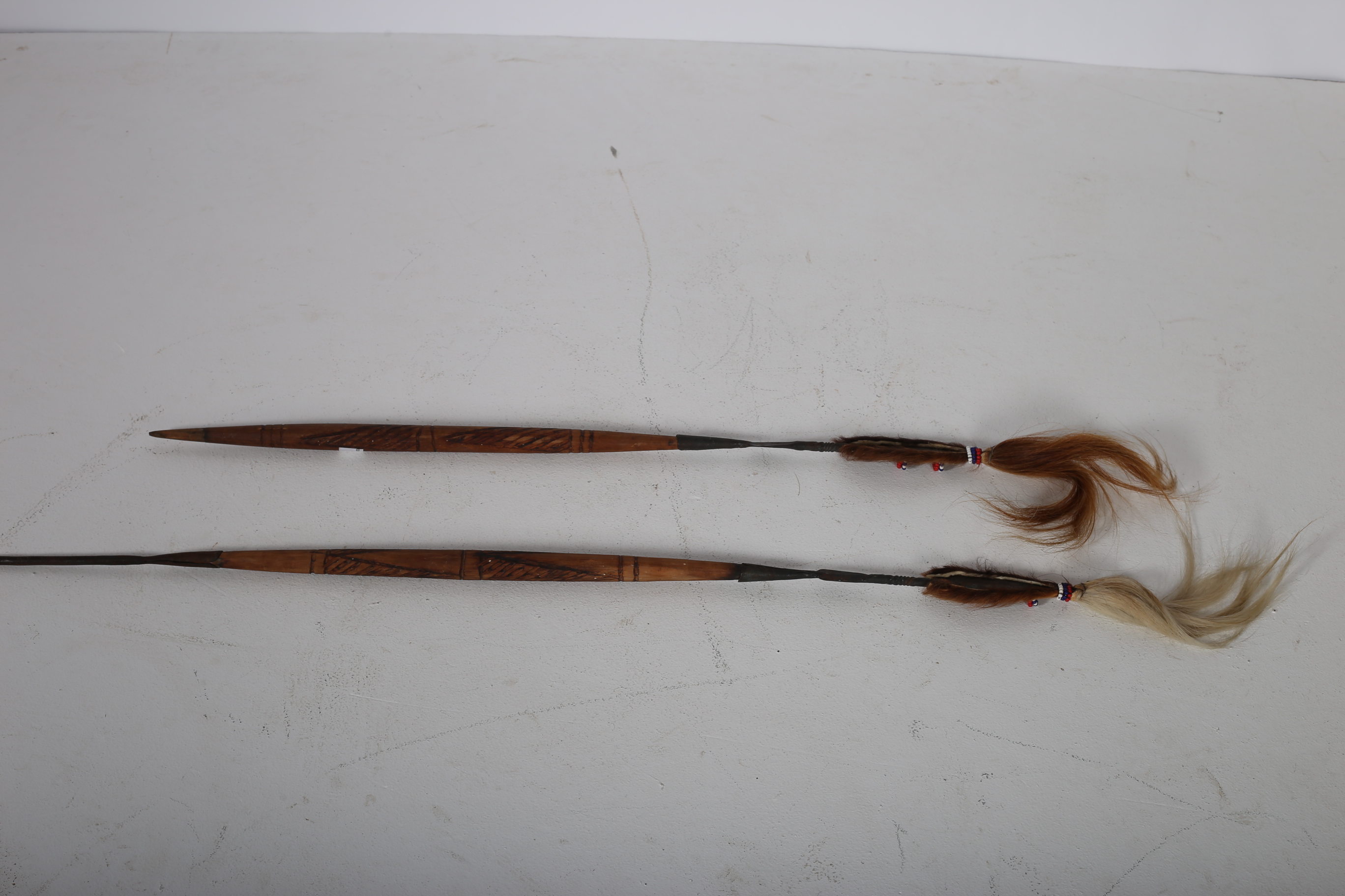 TWO INDIAN SPEARS with carved handles with hide sheathes