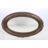 A CONTINENTAL GILT FRAMED MIRROR the oval bevelled glass plate within a reeded and flowerhead