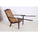 A PLANTATION HARDWOOD AND CANED ELBOW CHAIR with shaped seat the moulded arms on baluster legs