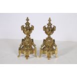 A GOOD PAIR OF BRASS FIRE IRONS each with an urn finial and Ram's head masks hung with floral