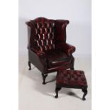 A WINE HIDE UPHOLSTERED BUTTON BACK LIBRARY WING CHAIR with scroll over arms and loose cushion on