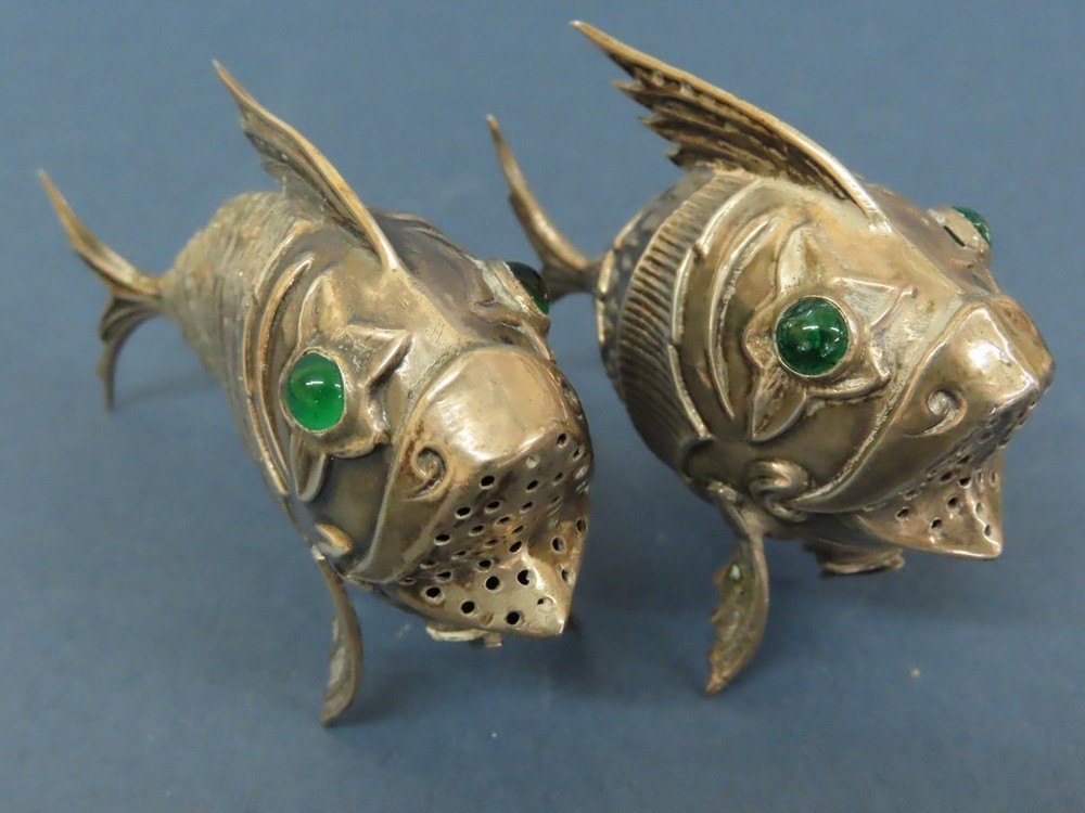An Oriental silver metal pepper in the form of an articulated fish with green glass eyes plus one