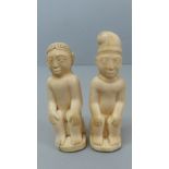 Two 19thC African carved ivory figures of two men seated with hands on their knees, one wearing a
