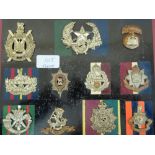 Twenty-three WWI / WWII British Army cap badges mounted on boards