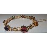 9ct gold bracelet set with seven semi-precious oval cabochon stones separated by bow shaped links.