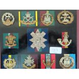 Twenty-three WWI / WWII British Army cap badges mounted on boards