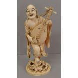 A good Japanese ivory Meiji period okimono of a man singing and playing a stringed instrument, red